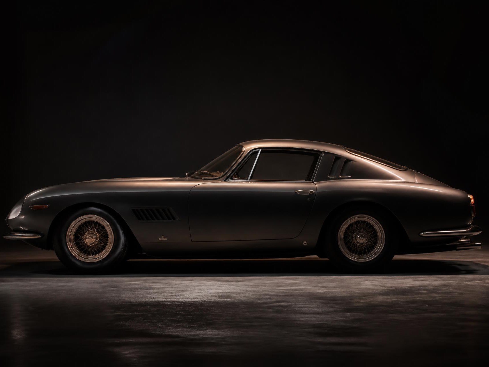 A classic grand tourer in side profile under a single light, from the Premier Automotive Collection site.